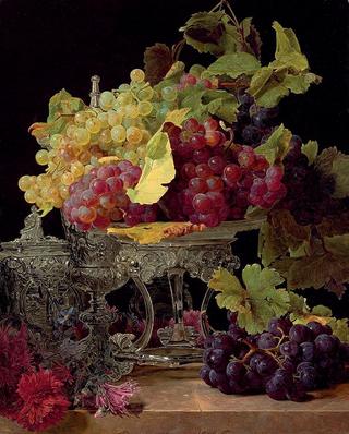 Red and white grapes and silver tableware on a marble ledge