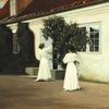 两个穿着白色长裙的年轻女孩在花园里摘玫瑰