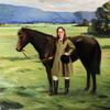 在田野里牵着一匹棕色小马的女孩
